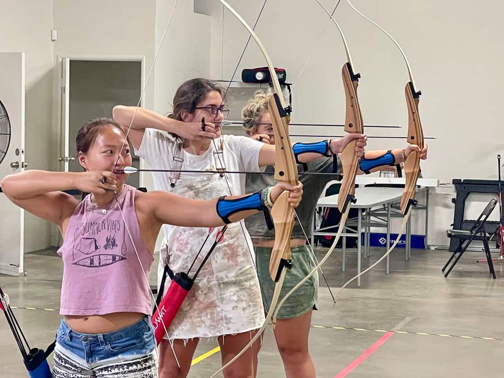 three girls drawing archery bows a fun indoor activity