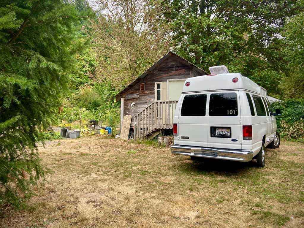 van parked in backyard using hipcamp to lower the budget on a road trip