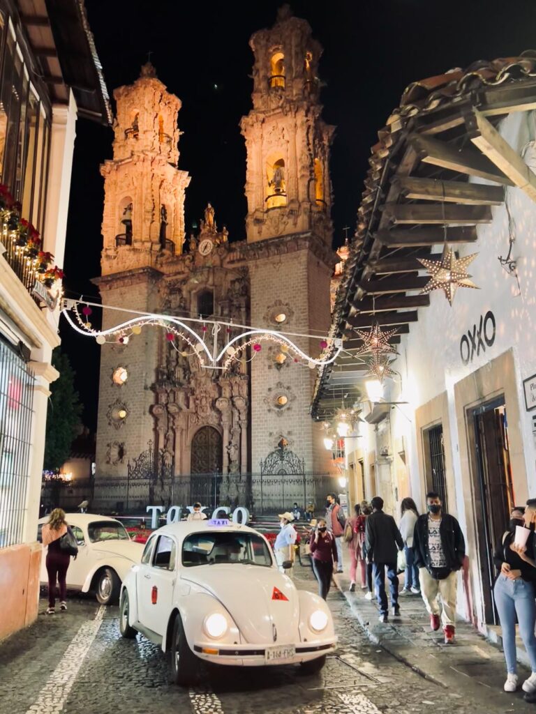 Volkswagen white taxi driving through taxco's center square