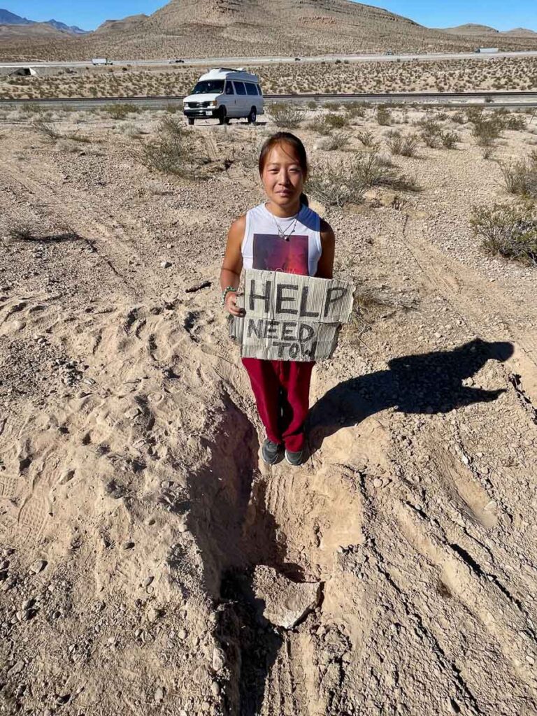 girl holding for help need tow sign in Las Vegas to page az desert road trip[