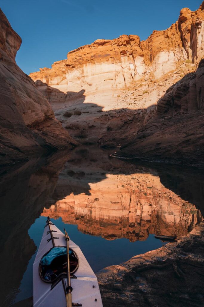 kayaking lake powell with reflection of cliff walls in sunset