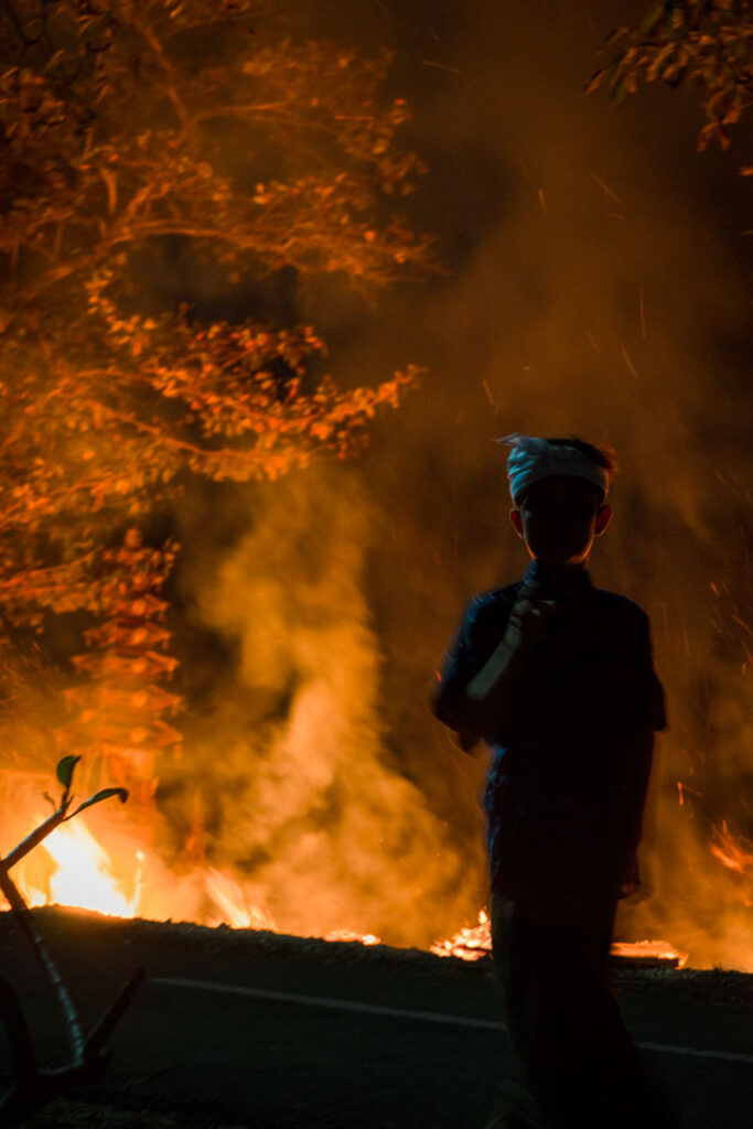 boy standing in front of cremation fire