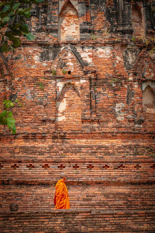 Wat Mahathat walking monk in front of ancient ruin