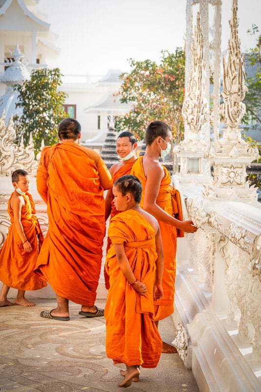 group of monks in golden hour at white temple chiang rai
