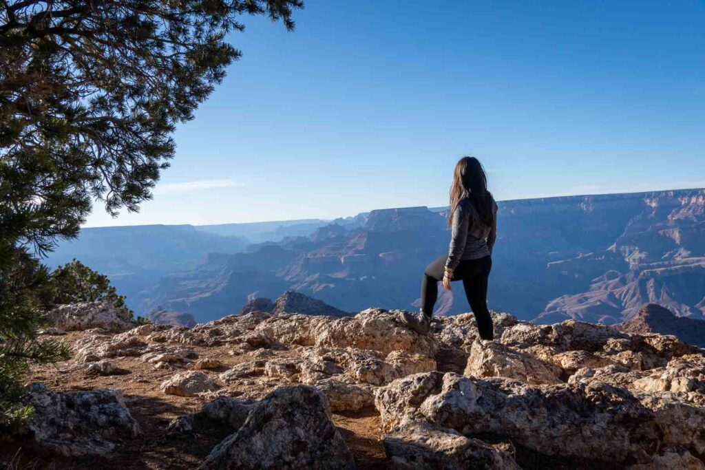 cat xu standing on some rocks looking out onto the grand canyon