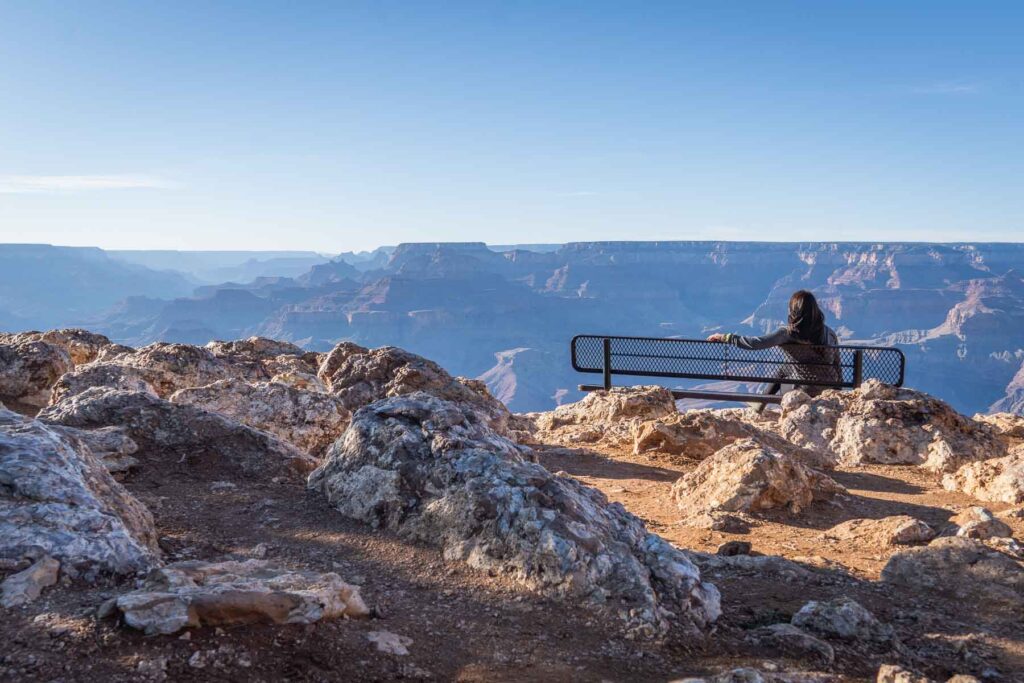 cat xu sitting on a bench looking out onto the grand canyon