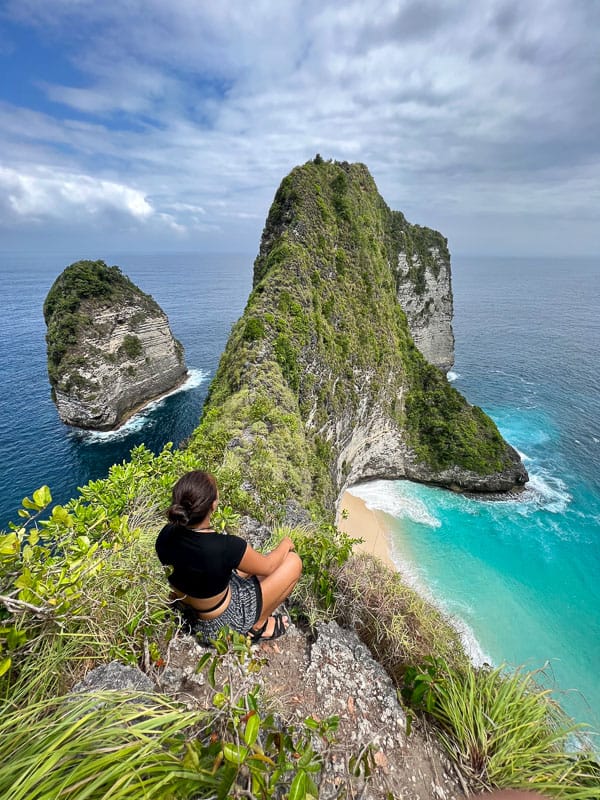 nomadicated sittting at Kelingking Beach's iconic cliffside viewpoint provides panoramic views of the ocean below and is an Instagram-worthy spot.