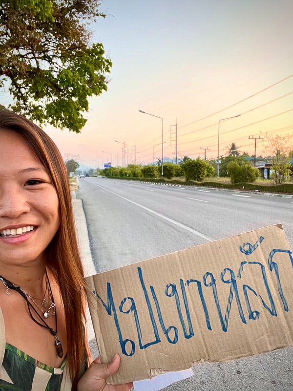 Nomadicated hitchhiking with sign in Ranong province