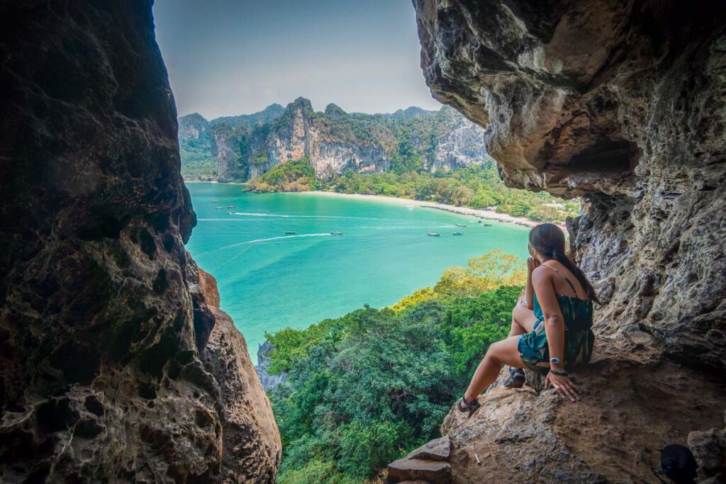 nomadicated looking through a cave onto Railay Beach's crystal-clear waters surrounded by towering cliffs