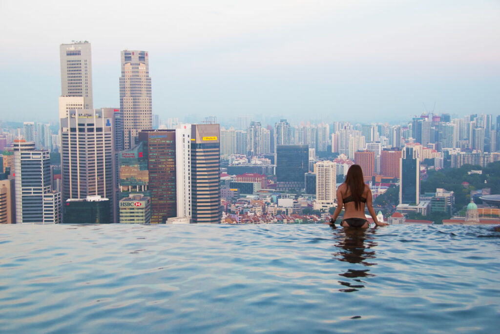 nomadicated in a bikini looking out onto the singapore skyline from the infinity pool of marina bay sands