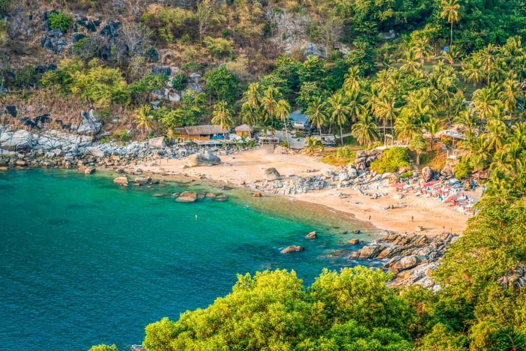 Secret Phuket beach with a stretch of golden sand lined with swaying palm trees