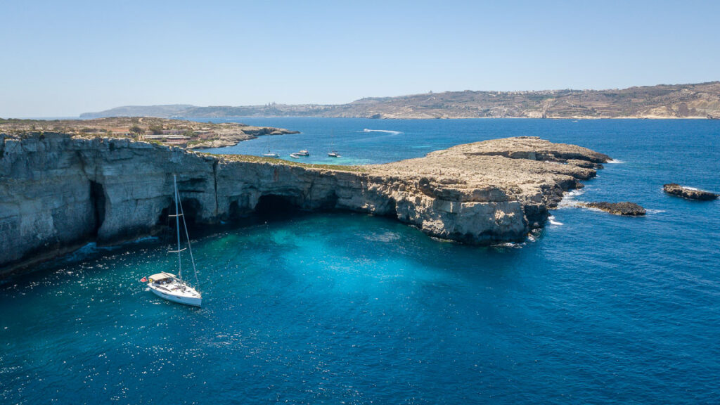 cliffs of comino island with a sailboat