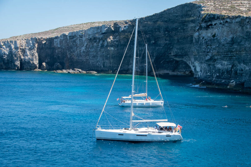 two sailboats anchored off comino island