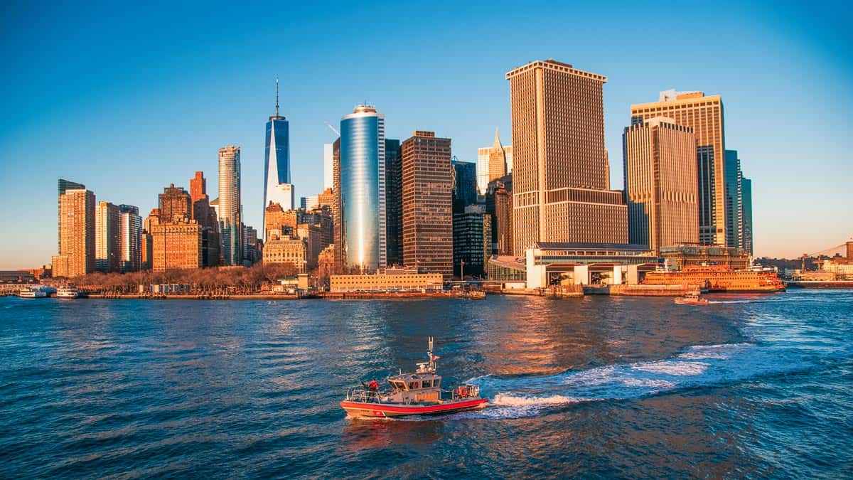 new york city skyline at sunset with a ferry driving across
