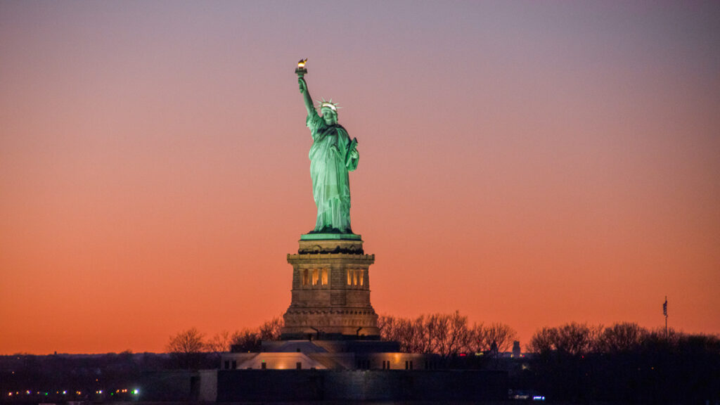 the statue of liberty at a colorful sunset, and iconic american symbol