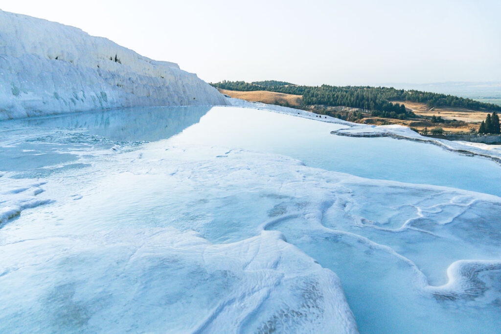 the glassy thermal pools of pamukkale flowing through the mineral deposits