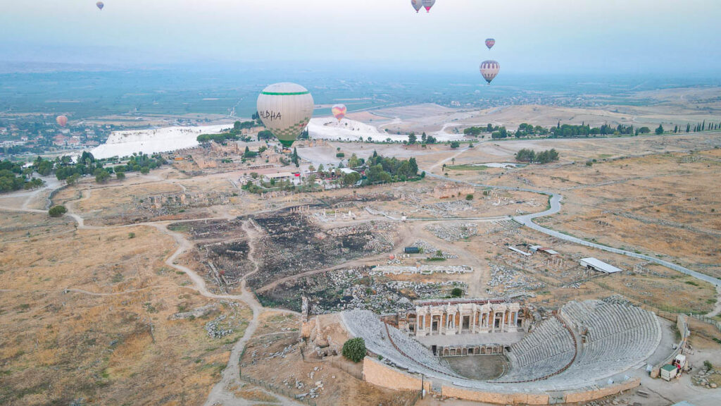 Experience the tranquility of a hot air balloon ride over Pamukkale, with the ancient ruins of Hierapolis in the background