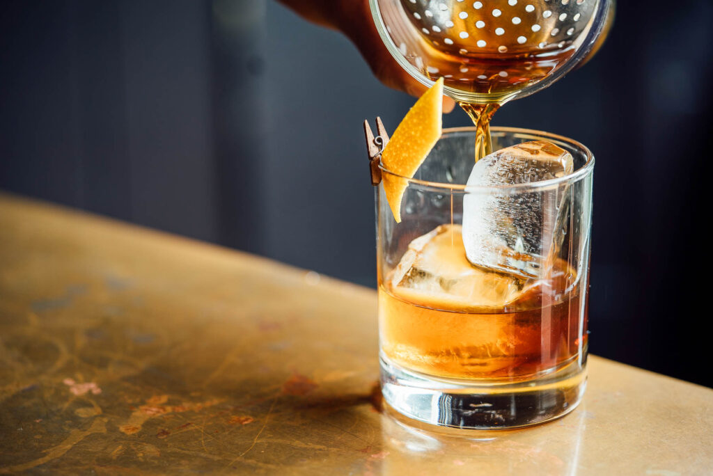 whiskey being poured into a glass on the rocks