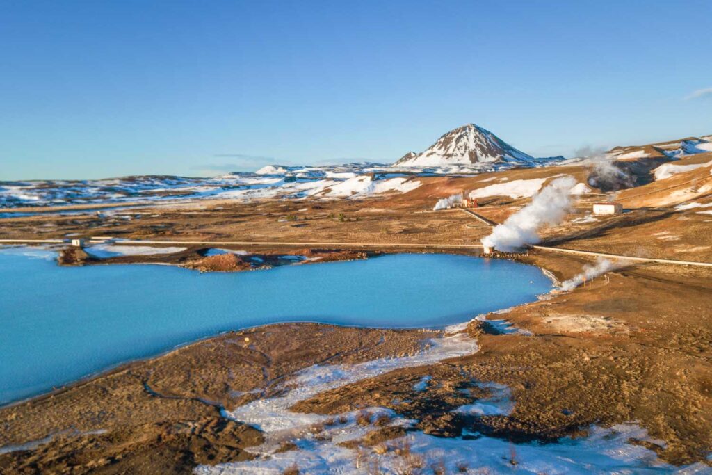 Blue Geothermal Lake in Iceland with snow covered hills