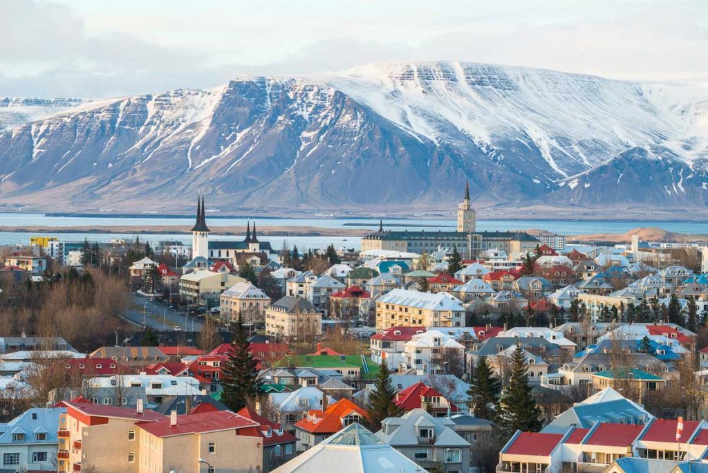 Iceland, Capital Region, Reykjavik city with colorful rooftops beneath snowcapped mountains