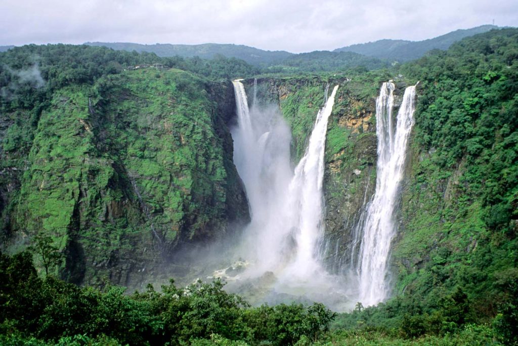 India, Karnataka, Jog Falls cascading through lush green cliffs into misty gorge