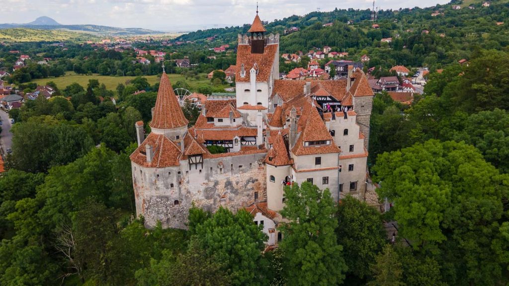 Romania, Bran, Bran Castle perched on a forested hill, a medieval fortress with red-tiled towers and stone walls overlooking the Transylvanian countryside