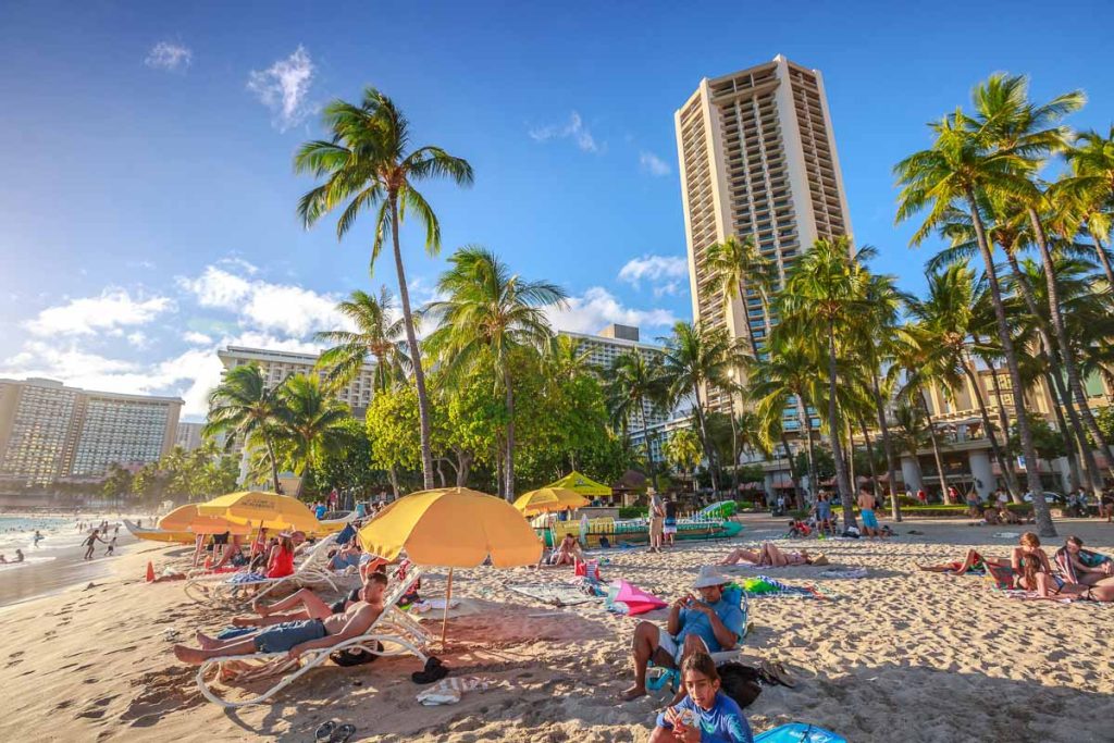 Waikiki, Oahu, Hawaii -tourist sunbathing on Waikiki beach at sunset. Waikiki beach, South Shore, is neighborhood of Honolulu and the most popular of Hawai.