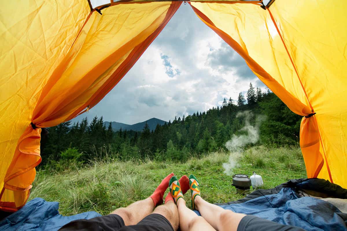 legs of a couples of man and woman in a tent outdoors