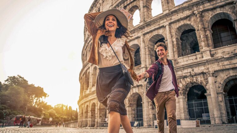 Young couple at the Colosseum, Rome - Happy tourists visiting italian famous landmarks