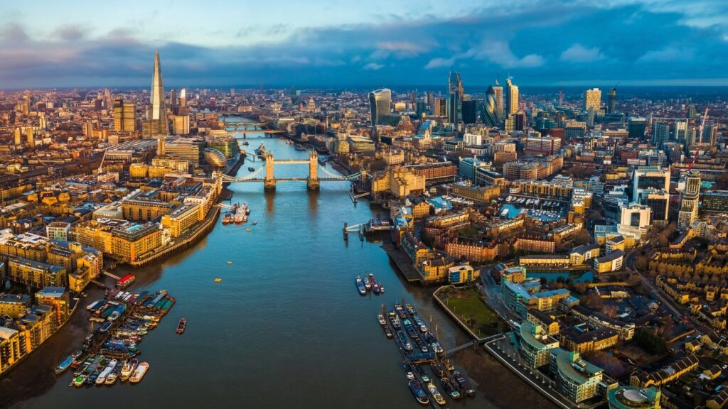 London, England - Panoramic aerial skyline view of London including Tower Bridge with red double-decker bus, Tower of London, skyscrapers of Bank District