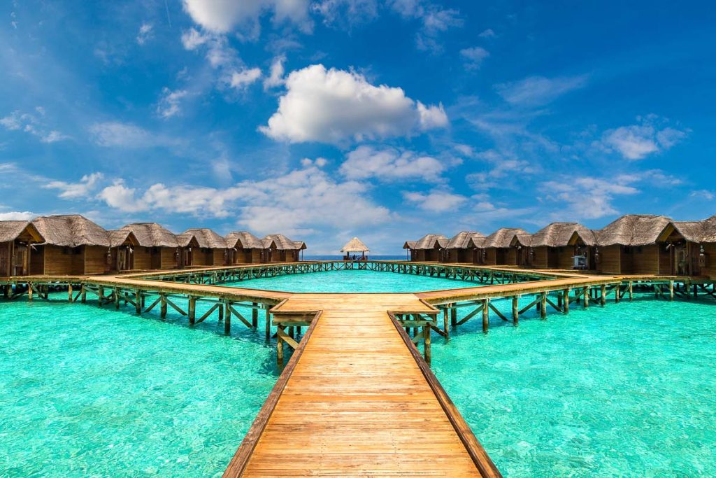 Water Villas (Bungalows) and wooden bridge at Tropical beach in the Maldives at summer day
