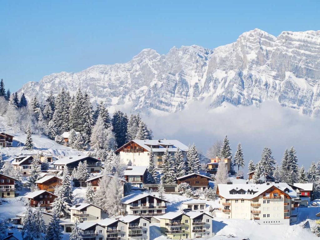 Switzerland, Swiss Alps, winter holiday village with snowy houses and mountains