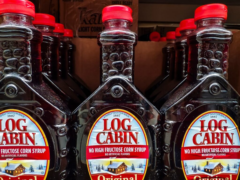 Close-up of Log Cabin syrup bottles lined up at the store.