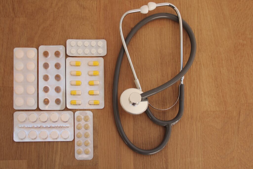 pills in blisters, medical stethoscope on a wooden table, top view, close-up, copy space