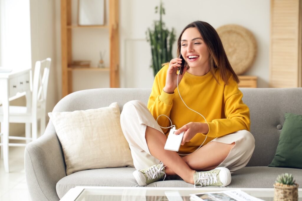 Young woman with phone and power bank at home