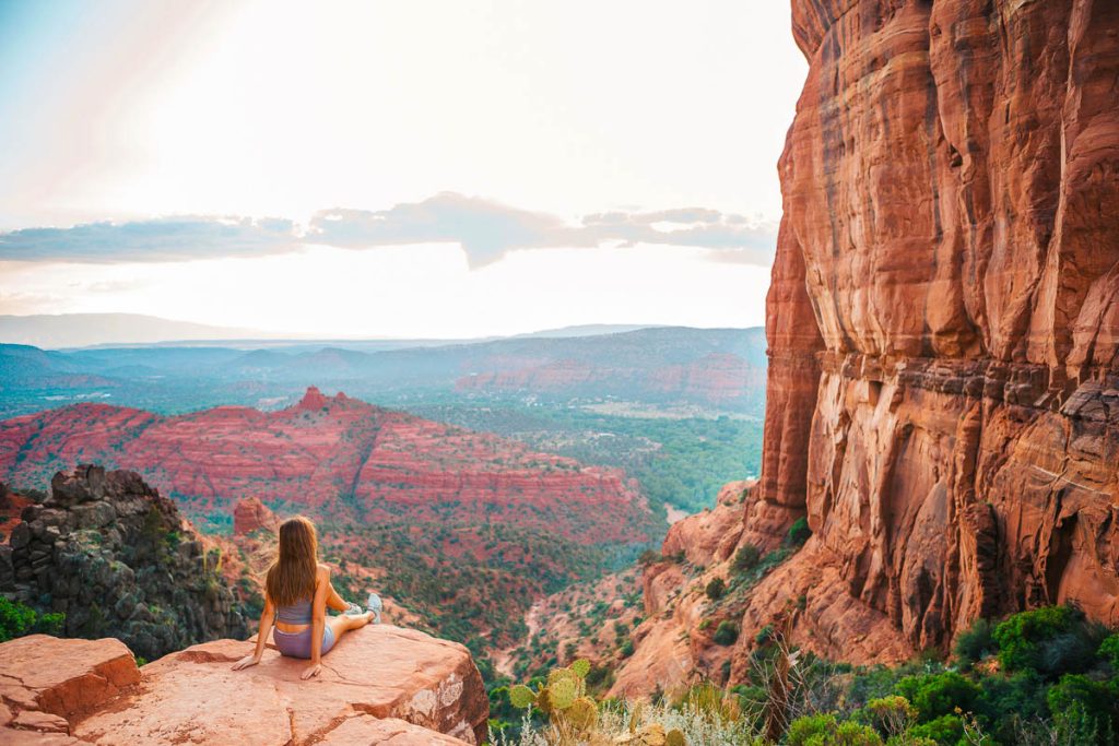 Back view of little girl on the edge of Cathedral Rock at sunset in Sedona, Arizona. View from Scenic Cathedral Rock in Sedona with blue sky in Arizona
