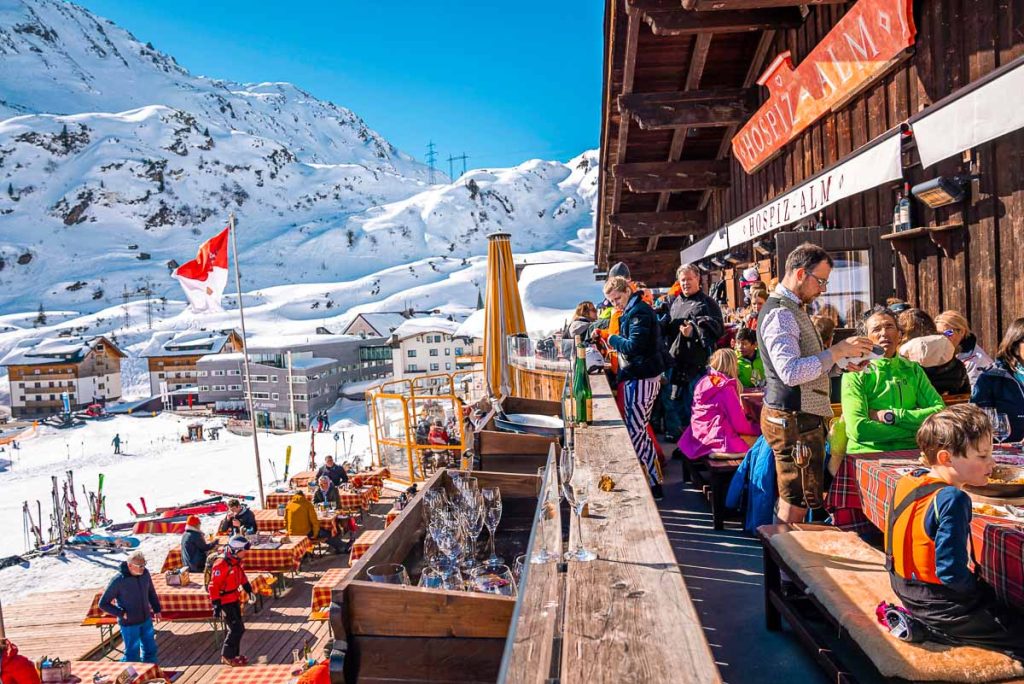 St. Anton am Arlberg. People sitting at outdoor cafe beside tables at ski resort chalet during skiing holiday, Tourists sitting at mountain cafe on sunny day