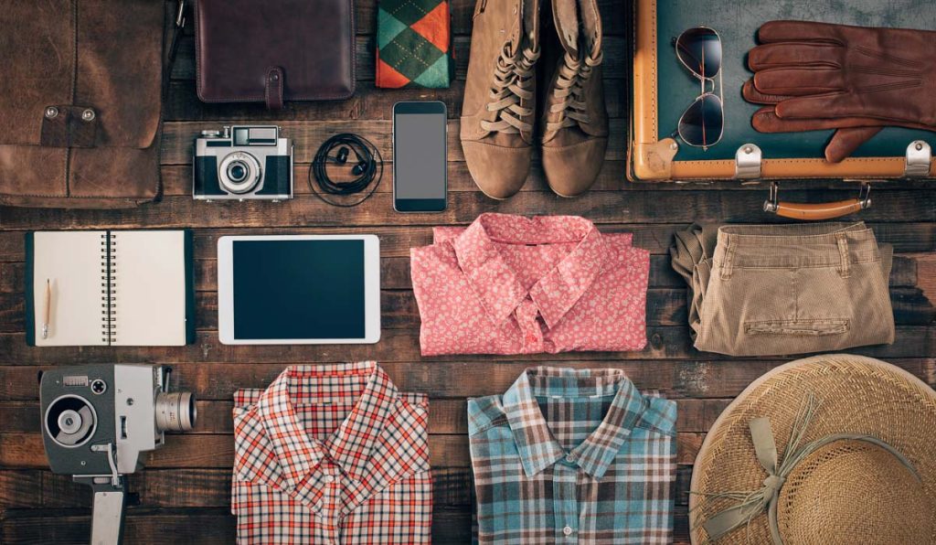 Hipster vintage accessories and clothing on a wooden table before packing, travel and vacations concept, top view