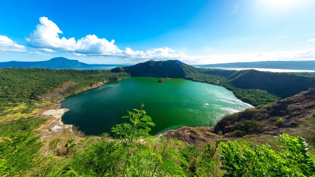 View of the cones of Taal Volcano and the emerald green waters of Lake Taal on a sunny day
