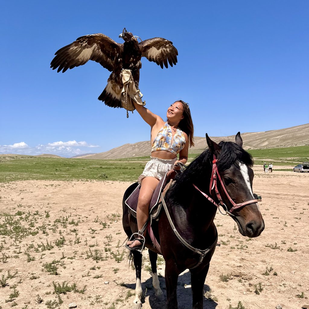 Cat Xu holding an eagle on a horse in Kyrgystan